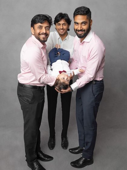 A playful moment with the uncles. Holding the baby upside down brings out genuine smiles and laughter, making for a memorable and fun family photo.