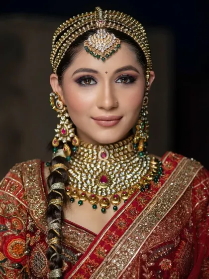 A close-up of this bride's regal look. The focus is on her dramatic braided hairstyle, smokey eyes, and the stunning matha patti.