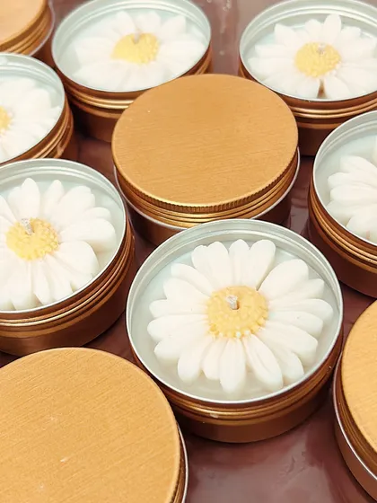 These daisy flower candles in tin containers are a durable and budget-friendly option for wedding favors. The tin is reusable and won't break.