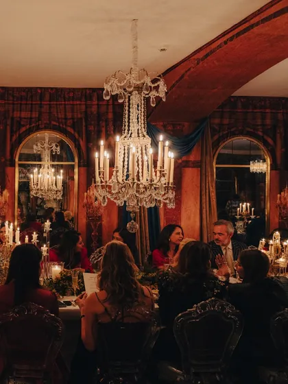 Guests engaged in conversation at the long, candlelit table during the Versailles dinner. The warm glow and elegant setting fostered an atmosphere of sophisticated conviviality.