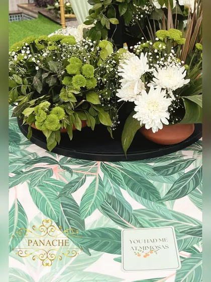 A detail of the tabletop, showing the tropical print linen, a floral arrangement, and a fun custom coaster.