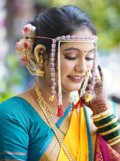 A soft and romantic pose, with the bride gently touching her face. This highlights her delicate mehndi and the flawless finish of her makeup.