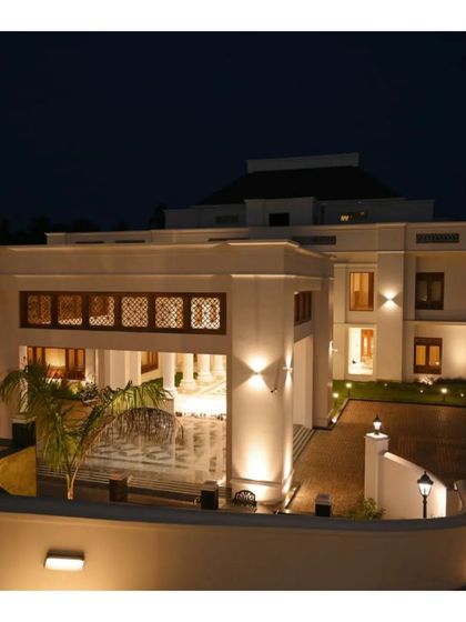 The same Kerala residence illuminated at night. The landscape and architectural lighting scheme is designed to highlight key features, creating a dramatic and welcoming ambiance while ensuring safety and circulation after dark.