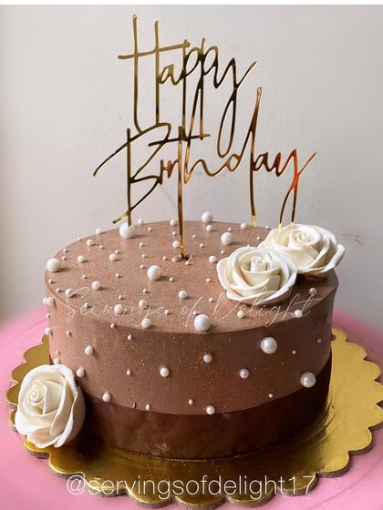 A rich chocolate ombre cake decorated with simple white pearls and sugar roses. It's a classic and elegant design for any birthday.