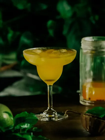 A moody shot of a passion fruit drink, with dark, leafy greens in the background creating a mysterious, tropical-night vibe.