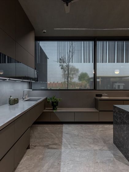 The long countertop run provides ample workspace, with under-cabinet lighting ensuring the area is well-lit. The design incorporates a seating nook by the window for a casual spot to relax.
