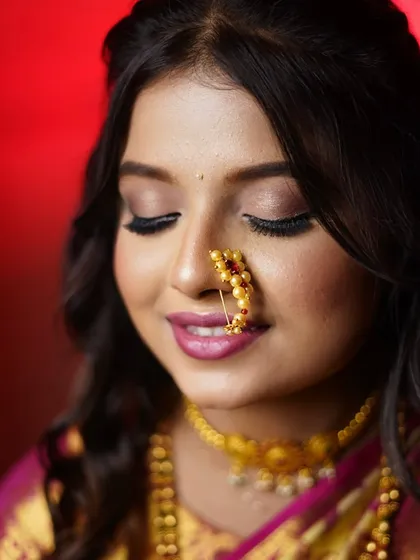 A serene portrait showcasing the soft gold shimmer on her eyelids and the classic pearl nath. The makeup is blended to perfection for a dreamy finish.