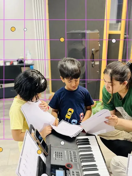 Two young students and their mentor go over sheet music at the keyboard. We ensure every child understands the fundamentals of reading music.
