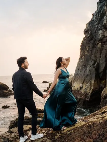 A dramatic pose on the rocky shores of Goa, with the bride's gown flowing in the wind. This image combines elegance with the raw beauty of the coastal landscape for a stunning pre-wedding portrait.