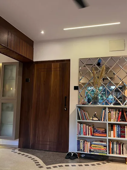 The entryway of this home features a solid wood door, a custom bookshelf, and a decorative beveled mirror wall that adds depth and elegance to the space.
