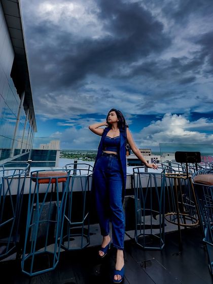 A wide shot showing the dramatic cloudy sky and the denim outfit. The setting is just as important as the clothes.