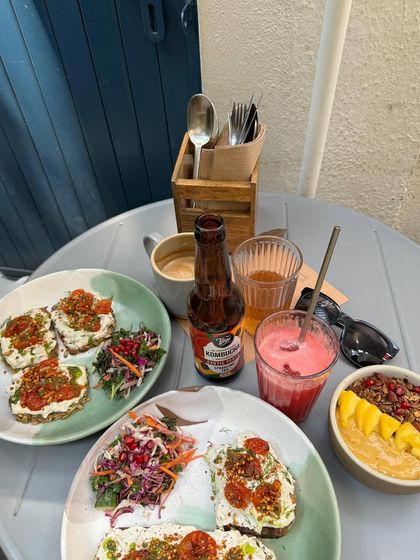 A beautiful brunch spread featuring our toast with house-made vegan cheese, a smoothie bowl, and fresh juices.