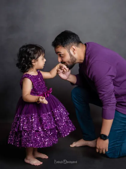 A truly precious moment between a father and his little girl, captured in our studio. The coordinated purple outfits add a touch of sparkle to this sweet, loving interaction.