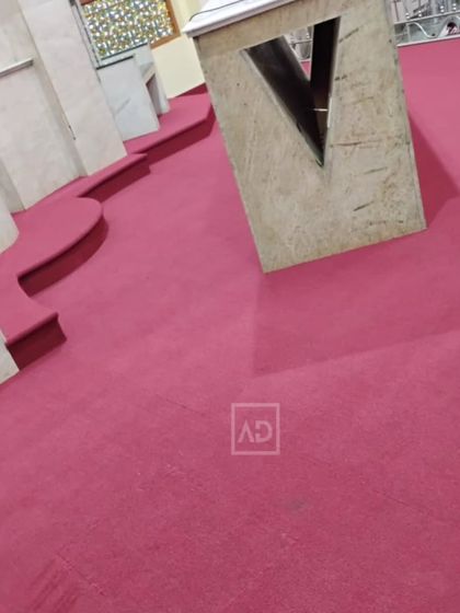 The carpet installed in a prayer hall, cut to fit around architectural features. The soft surface is comfortable for sitting or walking.