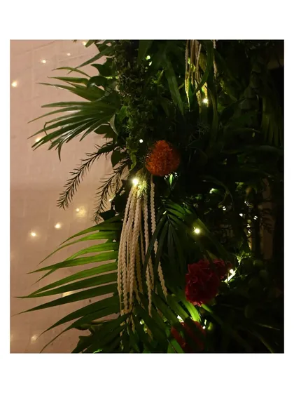 This close-up shows the rich textures of our Ganpati floral decor. We layered different types of palm leaves, ferns, and marigolds, intertwining them with delicate white tuberoses and warm fairy lights to create a lush and natural-looking festive arrangement.