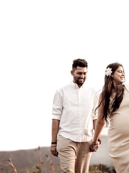 A joyful shot of the couple walking together, with a flower in her hair and a bouquet in her hand. Her smile is infectious.