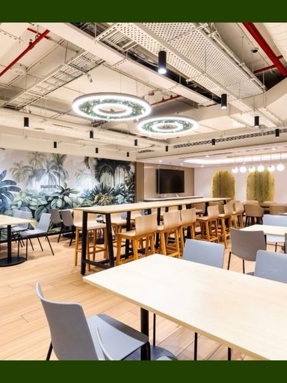 Another view of a large cafeteria space, this one featuring a beautiful nature-themed wall mural. We complemented the mural with live plants in hanging baskets and planters to create a cohesive, biophilic environment.