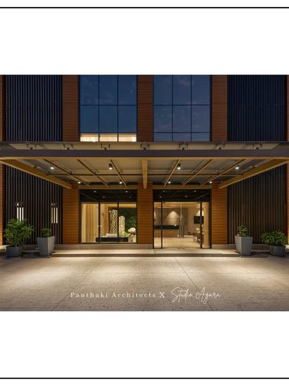 The entrance canopy of the modern office building. The design uses a combination of steel and glass to create a sleek, welcoming entryway, illuminated for a dramatic nighttime effect.