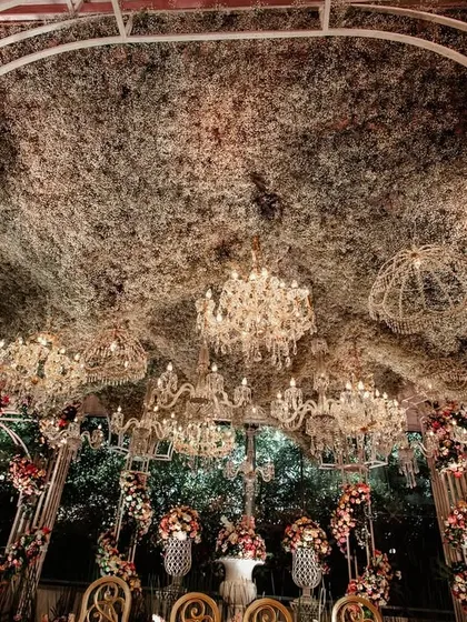 Looking up into the canopy of the mandap, this shot reveals the intricate web of foliage and the dozens of crystal chandeliers that create a magical, starlit effect.