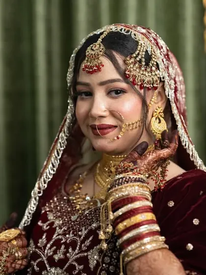 A beautiful portrait of a bride in her rich maroon lehenga, showcasing her intricate jewelry and elegant pose.