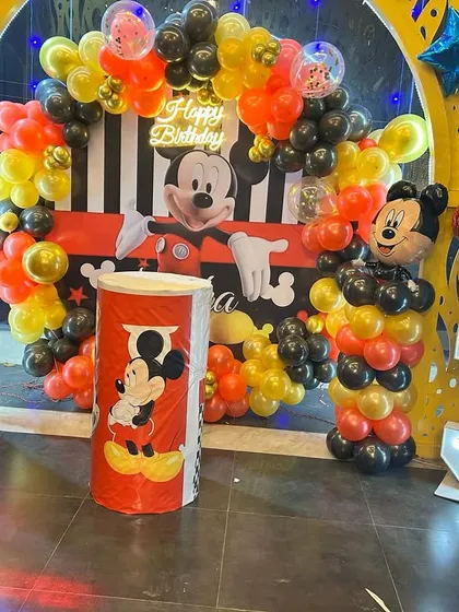 A classic Mickey Mouse theme birthday party for a 3-year-old. This setup includes character cutouts, themed balloon pillars, a marquee number '3', and a full backdrop for the cake table.