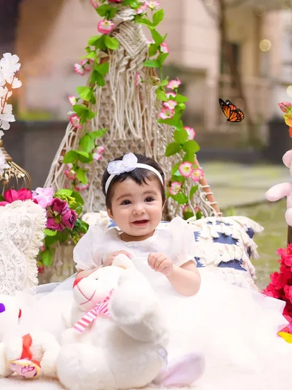 Surrounded by flowers and teddy bears, this little one is all smiles. The outdoor setting provides a gorgeous, naturally lit backdrop for her first birthday photos.