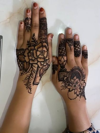 A lovely pair of complementary Arabic designs. One hand has a bold floral piece, while the other features a more delicate pattern with a heart shape.