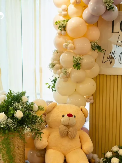 A close-up of the pastel balloon garland and oversized teddy bear from a picnic-themed baby shower. The soft colors and plush textures created a gentle and inviting atmosphere.