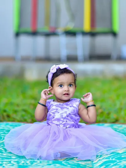Raising her hands in a sweet, spontaneous gesture. My approach to kids photography is to let them be themselves, which results in natural and charming poses like this one.