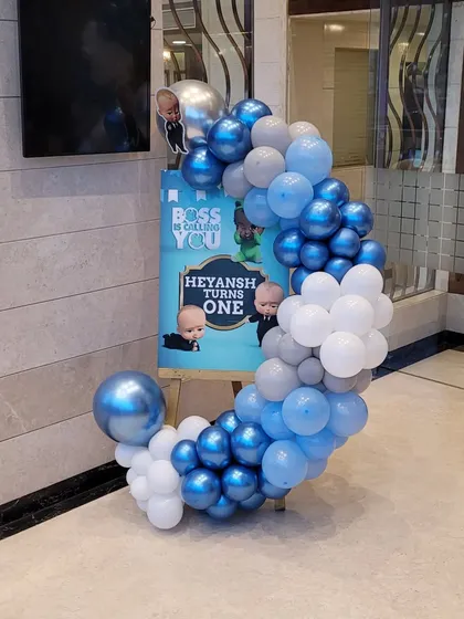 The personalized welcome sign for the Boss Baby party, framed by a stylish crescent-shaped balloon garland in the theme's colors.