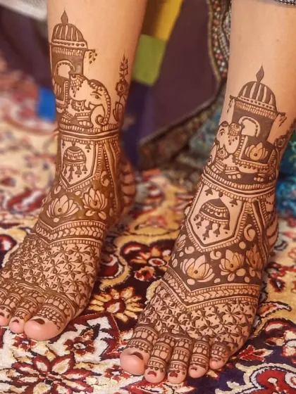 A beautiful bridal foot design with elephants and jhumkas, set against a lovely patterned rug.