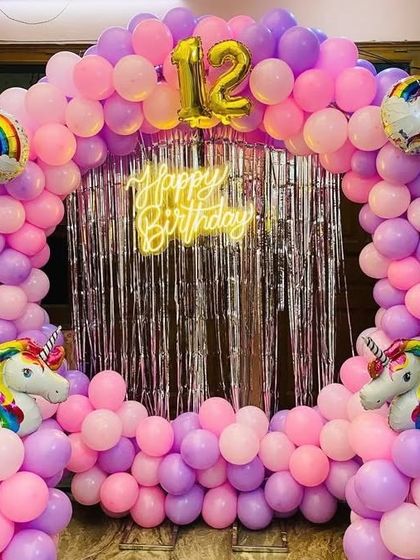 A magical unicorn-themed 12th birthday, featuring a pink and purple balloon arch, a silver shimmer backdrop, and unicorn foil balloons.