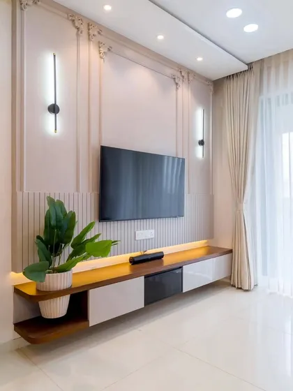 This elegant TV unit features a floating dual-tone console in wood and white, set against a wall with classic molding and fluted panel details. The vertical wall sconces add a touch of symmetrical grace to the setup.