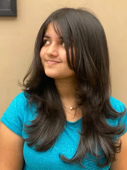 A side view of a client's new haircut, showing how the layers and bangs work together to create a beautiful, flowing style.