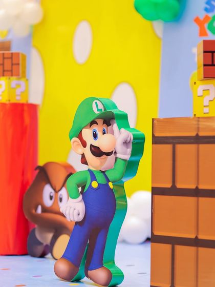 Here comes Luigi! A life-sized cutout of Luigi stands among other iconic Super Mario props like Goombas and question blocks, adding to the immersive feel of the Mushroom Kingdom.