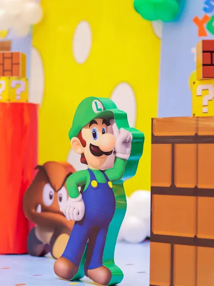 Here comes Luigi! A life-sized cutout of Luigi stands among other iconic Super Mario props like Goombas and question blocks, adding to the immersive feel of the Mushroom Kingdom.