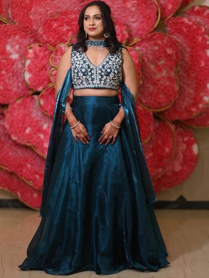 A full length view of this elegant wedding guest. The teal lehenga with its embroidered top is perfectly complemented by the soft glam makeup and hair.
