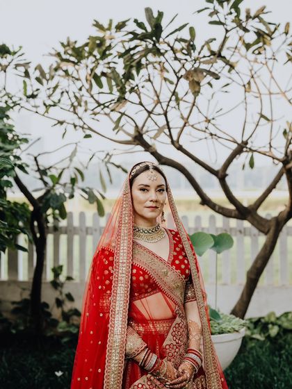 A beautiful outdoor portrait of the bride, Rocio, with a natural backdrop that complements her stunning red lehenga.