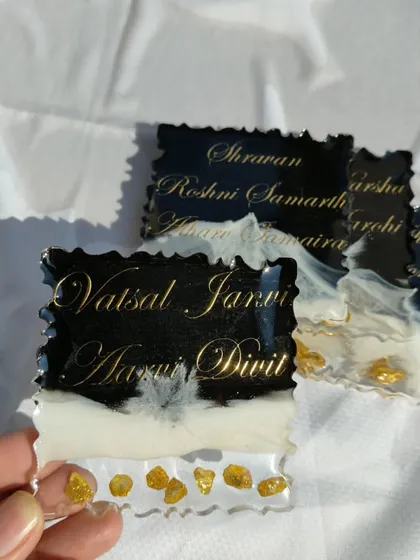 These custom fridge magnets feature family names in gold script on a striking black and white resin base with gold stones.