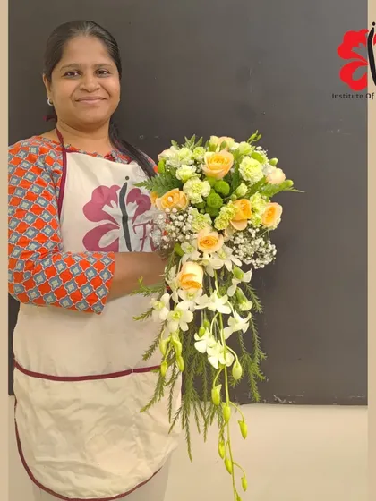 A student showcases her lovely cascading bridal bouquet. The design uses soft peach roses and white dendrobium orchids to create a classic and romantic feel, perfect for a wedding.