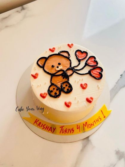 A cute bento cake with a teddy bear holding heart balloons for a 4-month milestone.