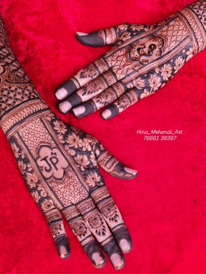 A close-up of the palm work, showing the couple's initials surrounded by a dense floral pattern, with the fingertips dipped for a dark, solid color.