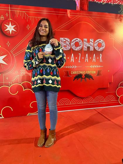 A happy participant at the Boho Bazaar Christmas Edition, posing with the ornament she created in our workshop.