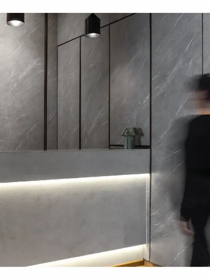 The reception area of our 'Shadows' law office project, exploring the grey area between black and white. The desk is lit from below, creating a soft glow against the grey, stone-like wall panels. The design is modern, formal, and atmospheric.