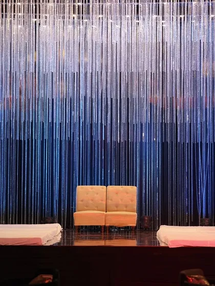 A straight-on shot of the serene yet opulent stage, with the shimmering crystal curtain perfectly centered behind the couple's loveseat.