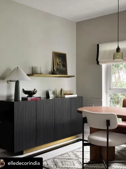 A black fluted sideboard with a brass-finished base, as seen in an Elle Decor feature. This piece adds texture and modern sophistication to the dining space.