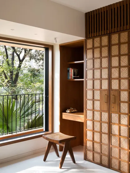 In this guest bedroom, I combined a custom wardrobe with handwoven paneling, an integrated study nook, and a matching stool. This approach to built-in furniture ensures every corner is functional while maintaining a cohesive, calming aesthetic using natural materials.