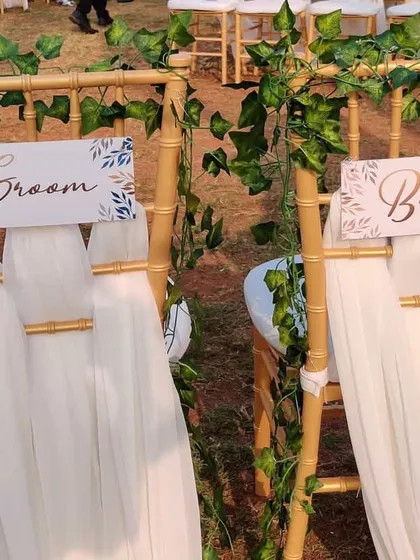Personalized "Bride" and "Groom" signs for the couple's chairs. We designed these with a delicate leaf motif and attached them to chairs decorated with ivy vines for a special touch.