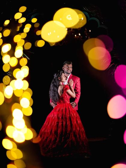 A dramatic and artistic shot using colorful bokeh to frame the couple in the light arch.