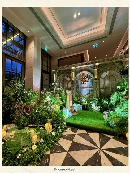 A wide view of the ruin-inspired mandap setup, showing how we integrate grand structural designs with natural elements like turf and dense foliage to create a complete, immersive environment.